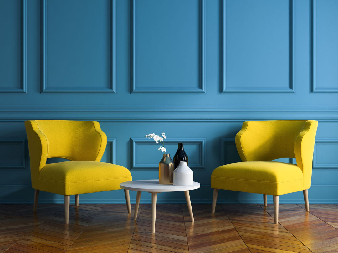 Two bright yellow lounge chairs in front of a deep blue accent wall.